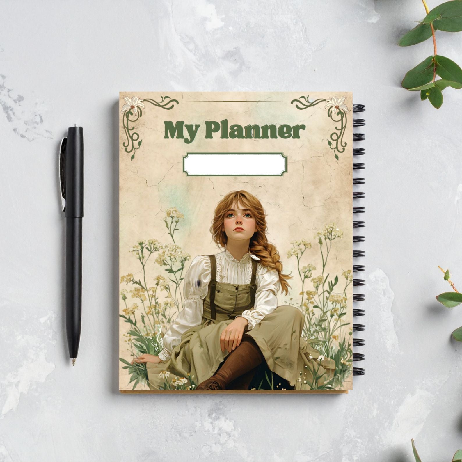 Anne of Green Gables planner with illustrated cover of girl sitting in wildflowers, displayed next to a pen on light background