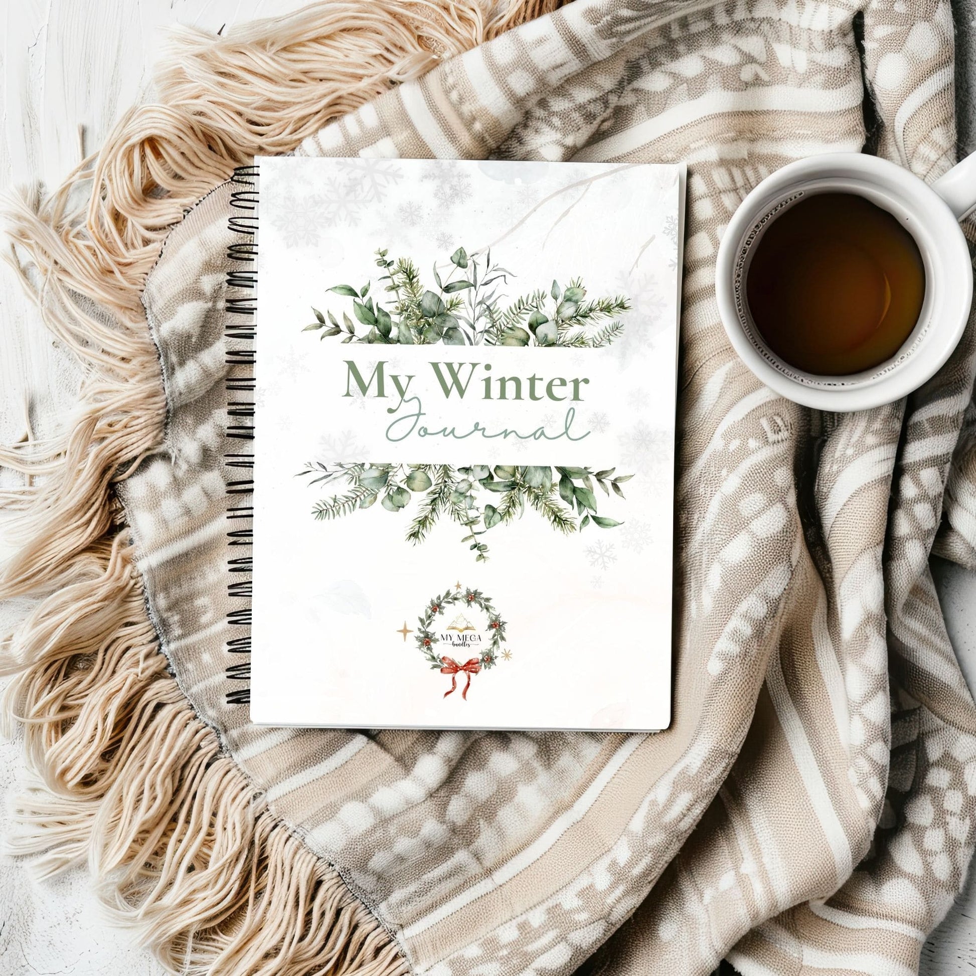 Winter journal with decorative cover on a textured blanket with a cup of coffee.