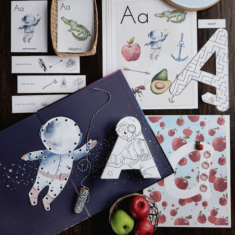 Preschool ALphabet Mega Bundle children's materials with alphabet and illustrations on a wooden surface